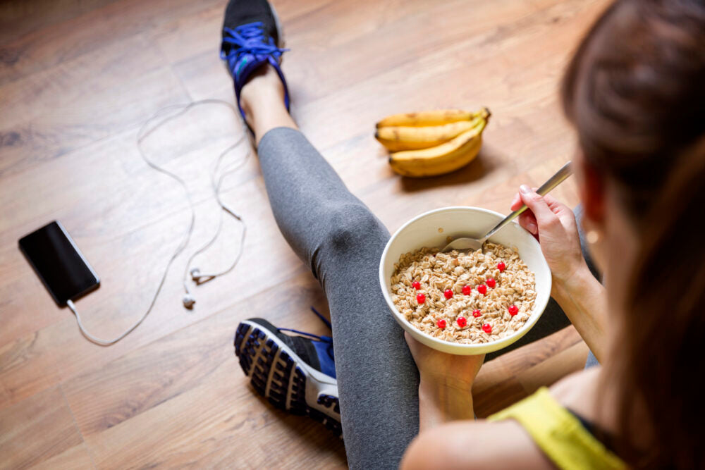 Mladé dievča je ovsené vločky s bobuľami po tréningu. Koncept fitness a zdravého životného štýlu.